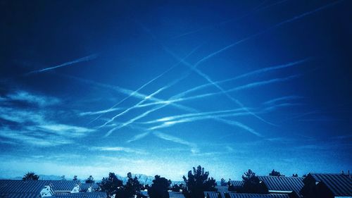 Low angle view of vapor trails in blue sky