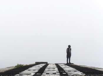 Rear view of man standing on footpath against sky