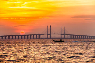 Bridge over sea against sky during sunset