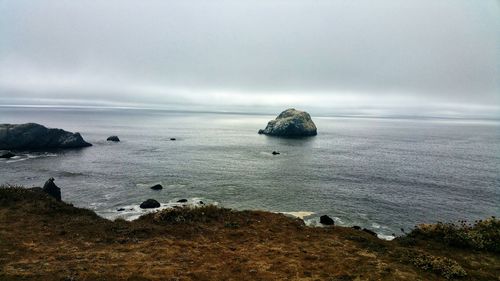 Surreal solitude. moody foggy light reflects against rock in the sea.