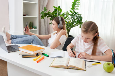 Mother and daughter sitting by desk at home