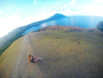 Person sitting on land against sky