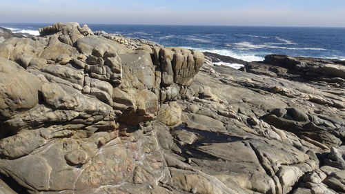 Rock formation on beach against sky