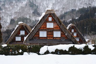 Snow covered house and trees against sky