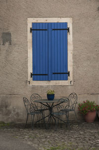 Empty chair against blue wall of building