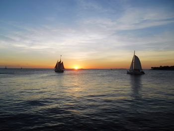 Sailboat sailing on sea against sky during sunset