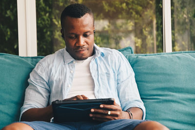 Man using mobile phone while sitting on sofa