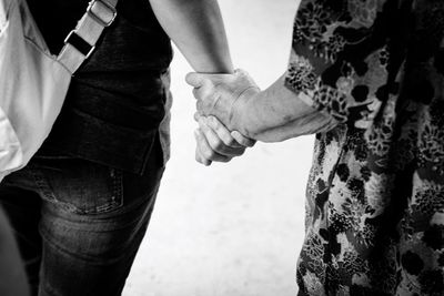 Adult woman and senior one holding hands