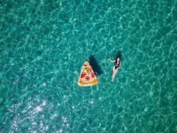 Directly above shot of woman swimming in sea by inflatable raft