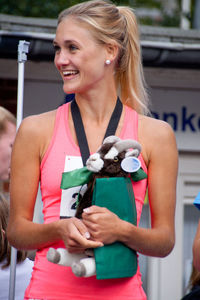 Cheerful young woman holding toy animal while standing outdoors