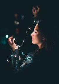 Close-up of young woman holding illuminated light