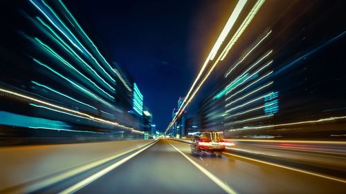 Blurred motion of car amidst illuminated buildings in city at night