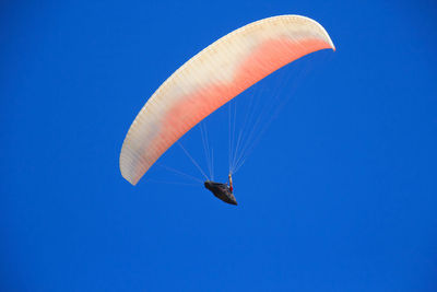 Low angle view of person paragliding against clear blue sky