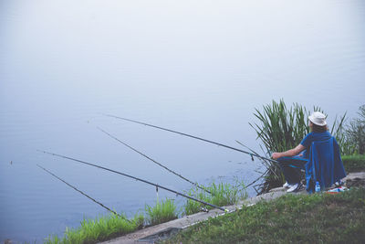 Rear view of woman sitting in sea against sky