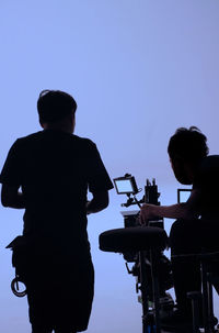 Rear view of silhouette people photographing against clear sky