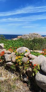 Scenic view of rocks by sea against sky