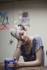 Young woman with mug sitting indoors