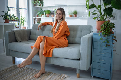 Young woman using laptop while sitting on sofa at home