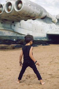 Rocker boy a child in black clothes stands against plane on the beach in summer in dagestan