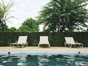 Chairs and swimming pool in park against sky