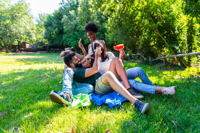 Side view of friends sitting on grassy field