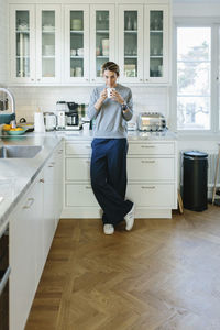 Woman standing with cup in kitchen