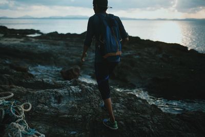 Rear view of man standing on rock at beach
