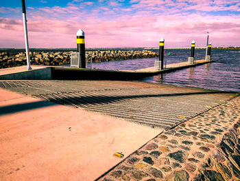 Footpath by sea against sky during sunset