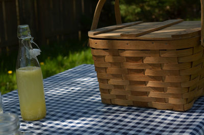 Vintage picnic basket, blue checked table cloth, bottles of lemonade and drinking jar glasses