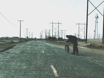 Rear view of man walking on road against sky