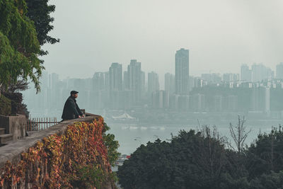 Man standing by buildings in city against sky