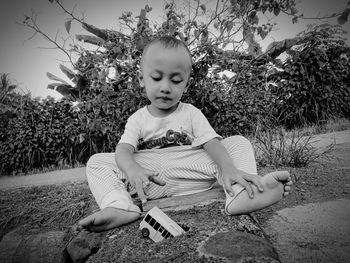 Cute baby boy plying while sitting outdoors