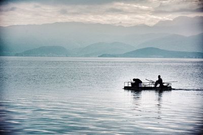 Silhouette men on boat sailing in lake