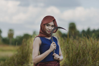 Thoughtful teenage girl holding knife while standing on field