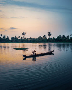 Man on boat in lake during sunset