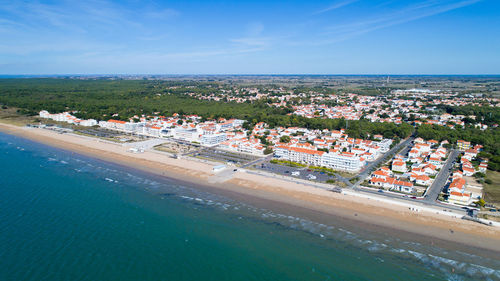 High angle view of town by sea against blue sky