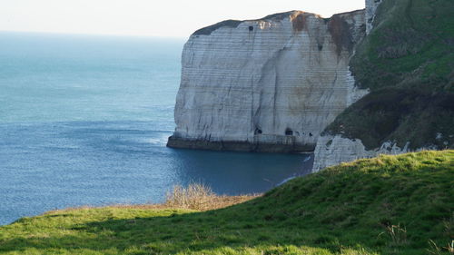 Scenic view of sea by cliff against sky