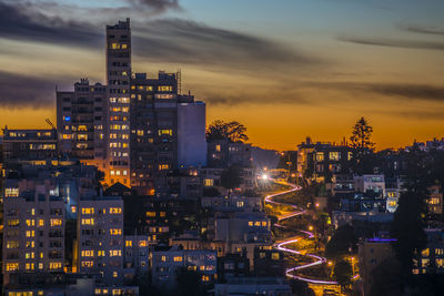 Illuminated cityscape against sky during sunset