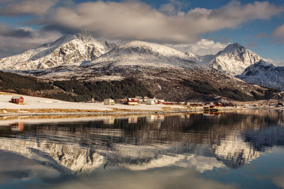 Scenic view of lake by snowcapped mountains against sky