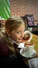 Portrait of girl with donut and hot chocolate at restaurant