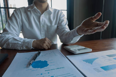 Midsection of man holding paper at table