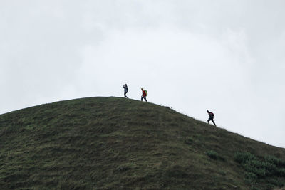 People walking on mountain against sky