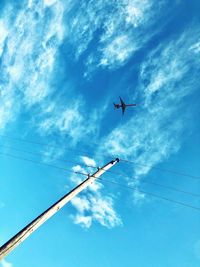 Low angle view of airplane flying against blue sky