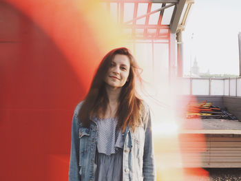 Beautiful young woman standing against red wall