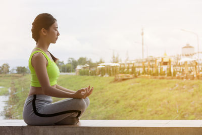 Side view of young woman practicing yoga