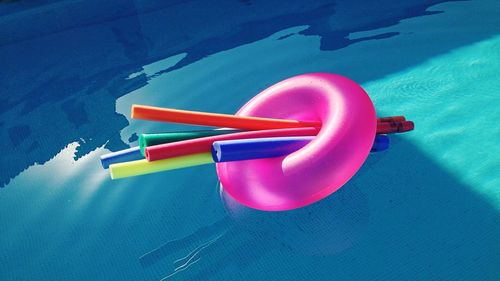 High angle view of pool noodle and inflatable ring floating on swimming pool