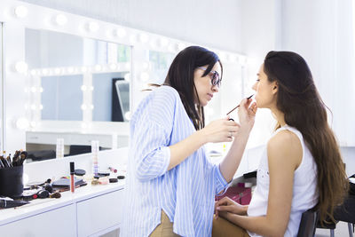 Beautician applying make-up on woman