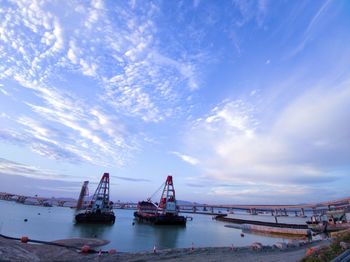 Cranes at commercial dock against sky