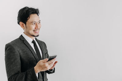 Young man using smart phone against white background