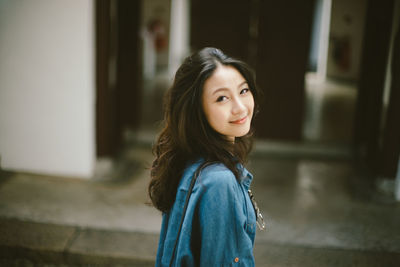 Portrait of smiling woman standing against wall